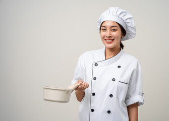 Young beautiful asian woman chef in uniform holding soup pot ladle utensils cooking in the kitchen...