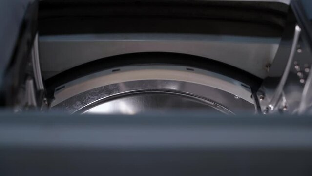 Slow peeking into a top-loading washing machine. Smooth movement of the camera to the drum of the washing machine