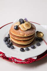Pancakes stack with banana and blueberries topping and bee honey breakfast food