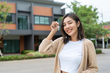 Woman buying or rent new home she holding key front of new house. Surprise happy young asian woman...