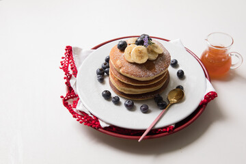 Pancakes stack with banana and blueberries topping and bee honey breakfast food