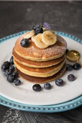 Pancakes stack with banana and blueberries topping and bee honey breakfast food