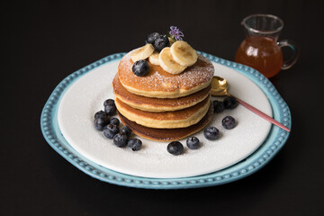 Pancakes stack with banana and blueberries topping and bee honey breakfast food
