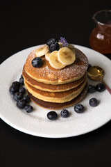 Pancakes stack with banana and blueberries topping and bee honey breakfast food