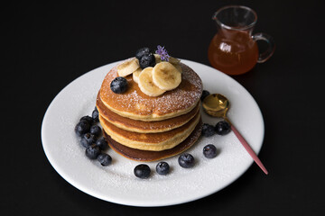 Pancakes stack with banana and blueberries topping and bee honey breakfast food