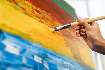 Close up hand Asian woman artist working on painting with brush and variant acrylic color. Female artist painter on canvas in creative studio as art concept