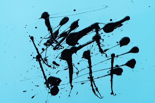 Top view of splashed in disorder thick black gouache on turquoise surface