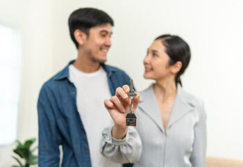 Fototapeta premium The couple asian family buying new house. Holding key Make a sale and purchase agreement with a real estate agent rent or purchase apartment home. Moving relocation