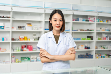 Beautiful asian woman pharmacist checks inventory of medicine in pharmacy drugstore. Professional Female Pharmacist wearing uniform standing near drugs shelves counter