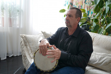 a man sits on a couch and plays the drum