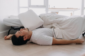 Asian man falling down from the bed lying on the floor at home.