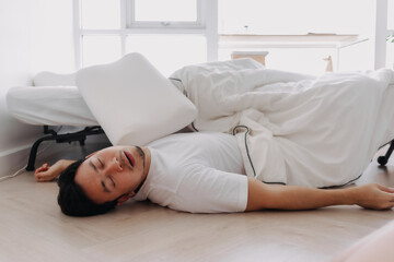 Asian man falling down from the bed lying on the floor at home.