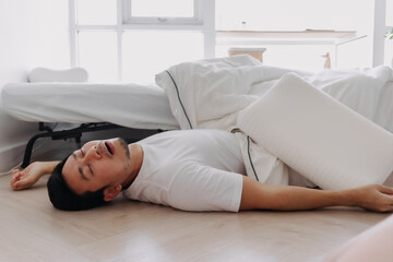 Asian man falling down from the bed lying on the floor at home.