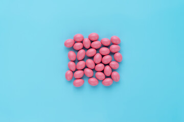 Top view of thirty Easter eggs covered with bright pink color and lying disorderly on turquoise surface 