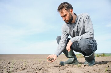 A farmer checks quality of soil before sowing.