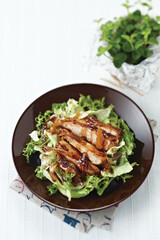 검은접시에 채소를 담고 닭요리를 얹은 후 발사믹소스로 드레싱한 발사믹드레싱치킨샐러드