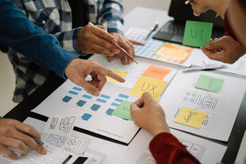 ui designer brainstorming about mobile app interface wireframe design with customer breif and color code at office.