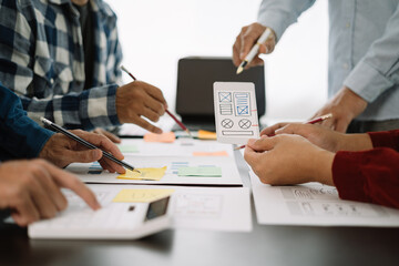 ui designer brainstorming about mobile app interface wireframe design with customer breif and color code at office.