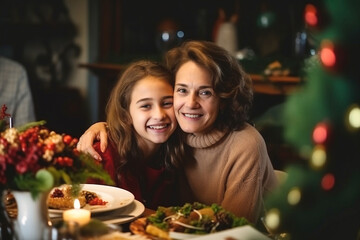 Obraz na płótnie Canvas Winter holidays and people concept - grandmother with her granddaughter at the table celebrates christmas and new year. Home holiday. Blurred background. Selective focus.