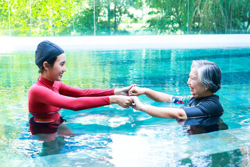 Elderly person doing physiotherapy in water. Female staff doing physiotherapy for seniors. exercise...