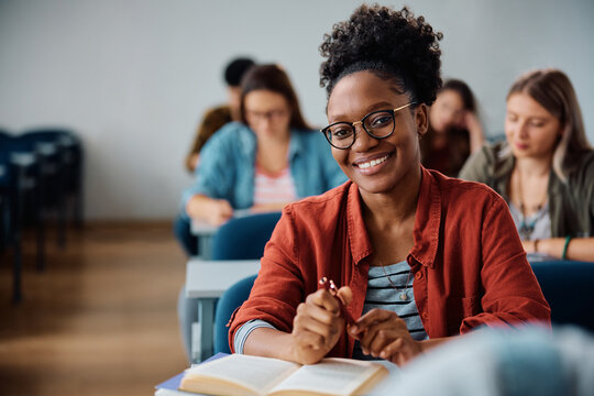 Happy black females student during class in lecture hall looking at camera.
