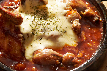 Grilled chicken with spicy sauce and cheese on an iron plate