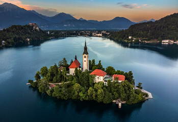 Bled, Slovenia - Aerial view of Pilgrimage Church of the Assumption of Maria at Lake Bled (Blejsko Jezero) with Bled Castle (Blejski Grad) and Julian Alps at backgroud on a summer afternoon at sunset