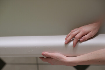High angle view of sensual female hands holding to side of bathtub filled with cloudy water   