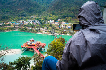 Tourist capturing Dhari Devi Hindu temple in Alaknanda river, Rudraprayag, Uttarakhand, India....