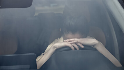 Businesswoman sits in car with sad and upset expression. Black-haired woman scared to drive own car...
