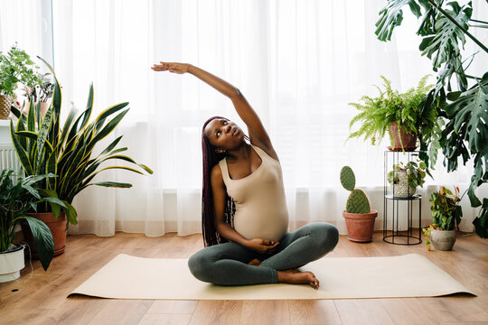 Black pregnant woman doing exercise during yoga practice