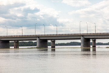 Concrete bridge across the river against the backdrop of clouds with the sky