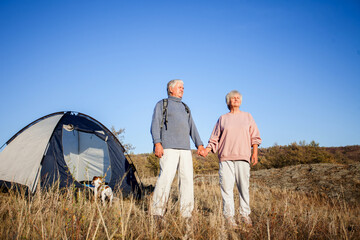 Senior Man and woman looks into the distance near the tent at campsite