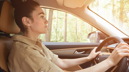 Black-haired businesswoman driver singing favourite song in automobile with excited expression on face. Lady enjoys listening to music during ride, sunlight