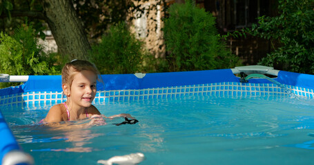 Little girl having fun with toys in the garden swimming pool.
