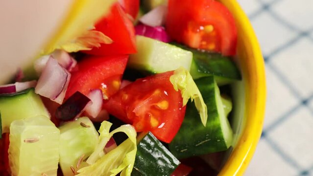 Kachumber Salad is the Indian cucumber, tomato, and onion salad. The girl pours lemon juice on a salad with cumin seeds, a fresh, easy chopped salad. The vegetables are dressed with lemon juice 