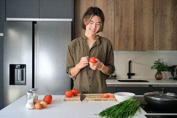 Smiling asian young man cooking at kitchen.