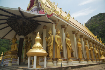 The golden standing Buddha images are enshrined around the Buddhist Church at Wat Thamkrabok. Located at Saraburi Province in Middle of Thailand.