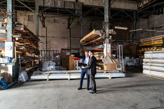 Two businessmen with folder talking in an old storehouse