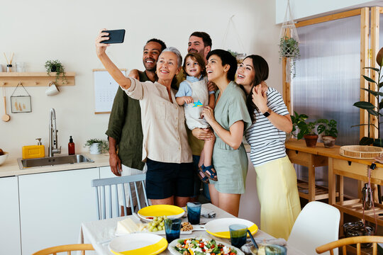 Smiling family taking selfie with smart phone in kitchen