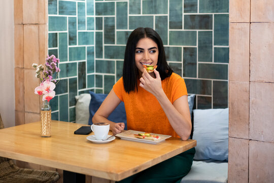 Young woman enjoying snacks with coffee in cafe
