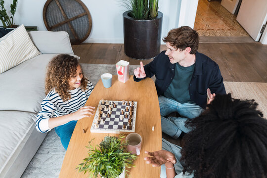 Parents sitting in livingroom teaching daughter to play chess