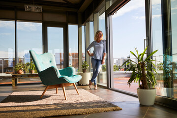 Mature woman standing at the window at home looking out