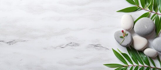 Spa background concept with white stones, towel, and green plant leaves on a marble background....