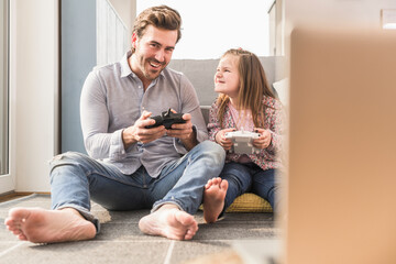 Young man and little girl playing computer game with gaming console