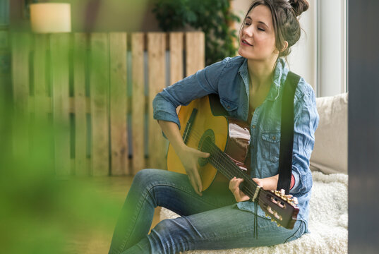 Passionate woman playing guitar at home