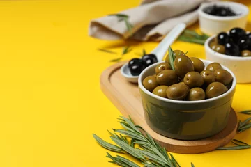 Foto op Plexiglas Olives in bowls and wooden stand on yellow background, space for text © Atlas