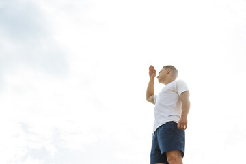 A man looks into the distance, his hand is raised to the mountain