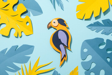 Yellow and blue tropical leaves in pastel shades on a blue background, with a parrot
