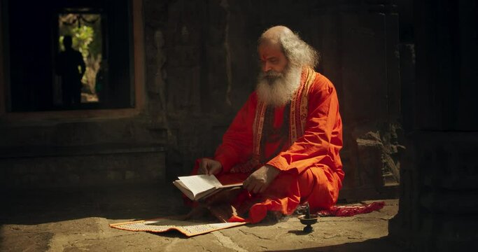 Slow Motion Portrait of Old Indian Monk Reading a Book in an Ancient Temple. Senior Guru Getting Wisdom from Sacred Texts, Humble Male Devoted to Hinduism, Gaining Knowledge and Spiritual Connection